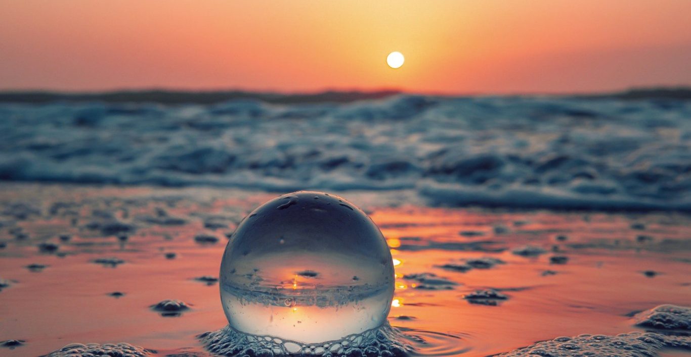 Thai-Massagen für Körper und Seele Sonnenuntergang über dem Meer, mit goldenem Licht und einem weiten Sandstrand.